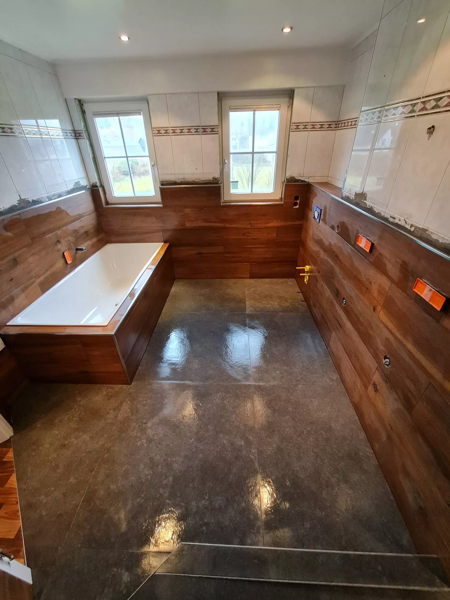 Badezimmer im Bau mit Wandfliesen in Holzoptik und dunkler Bodenfliese