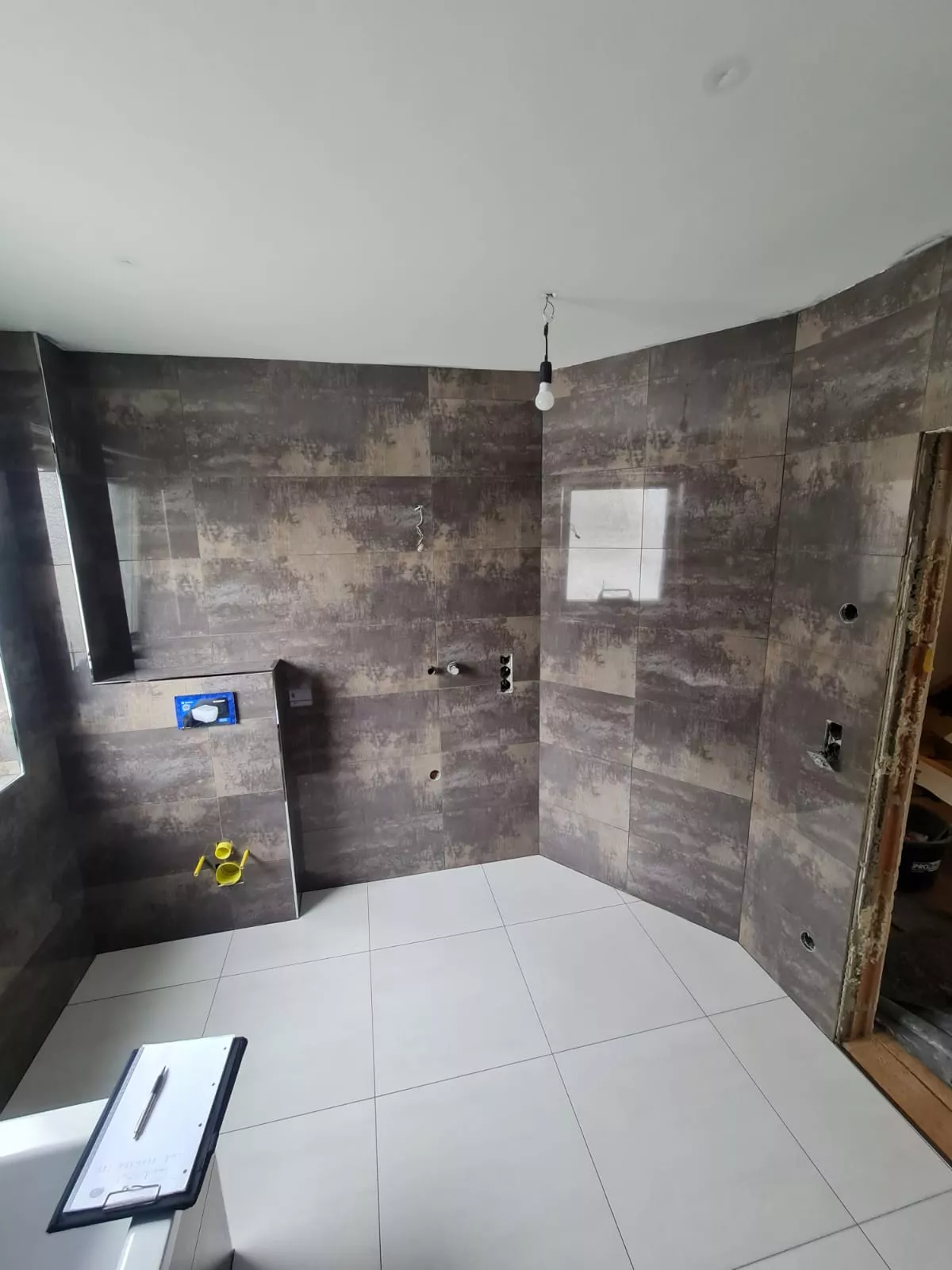 Badezimmer im Rohbau mit Wandfliesen in dunkler Metall-Beton-Optik